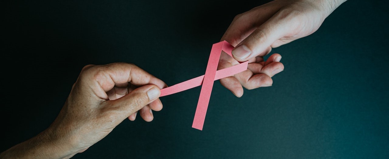Person holding a pink ribbon | Breast Cancer Car Donations