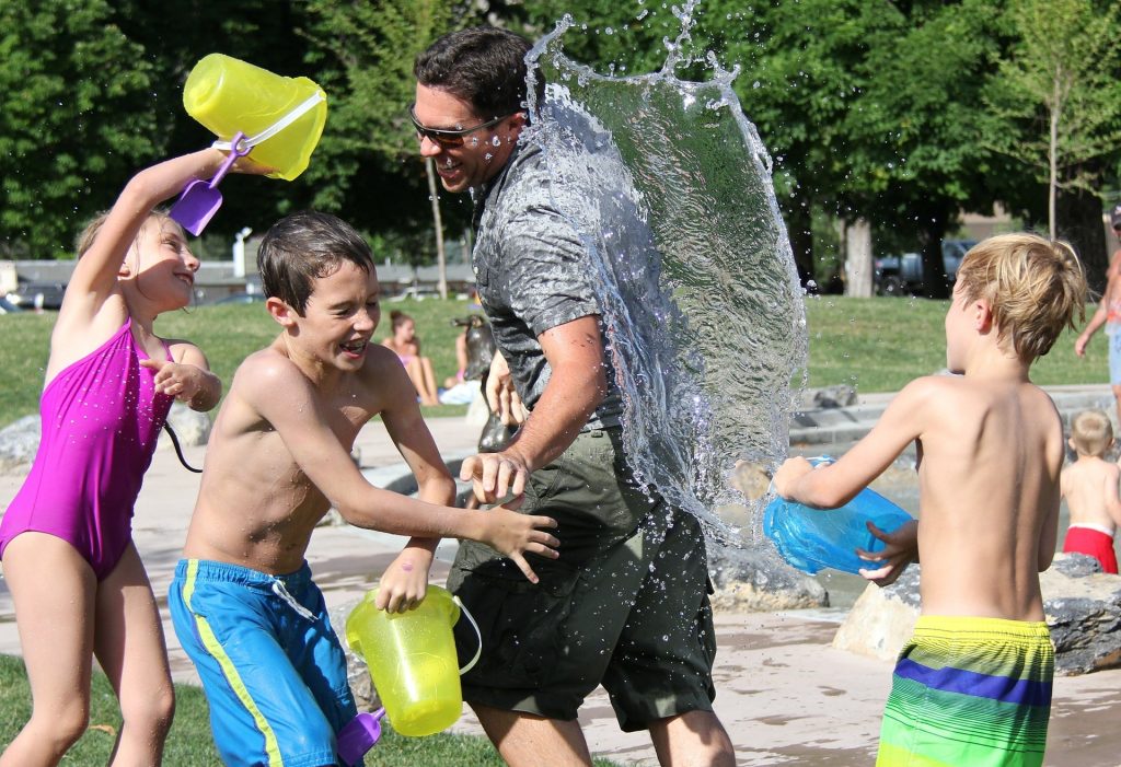 Father with his kids in a water fight | Breast Cancer Car Donations