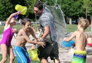Father with his kids in a water fight | Breast Cancer Car Donations