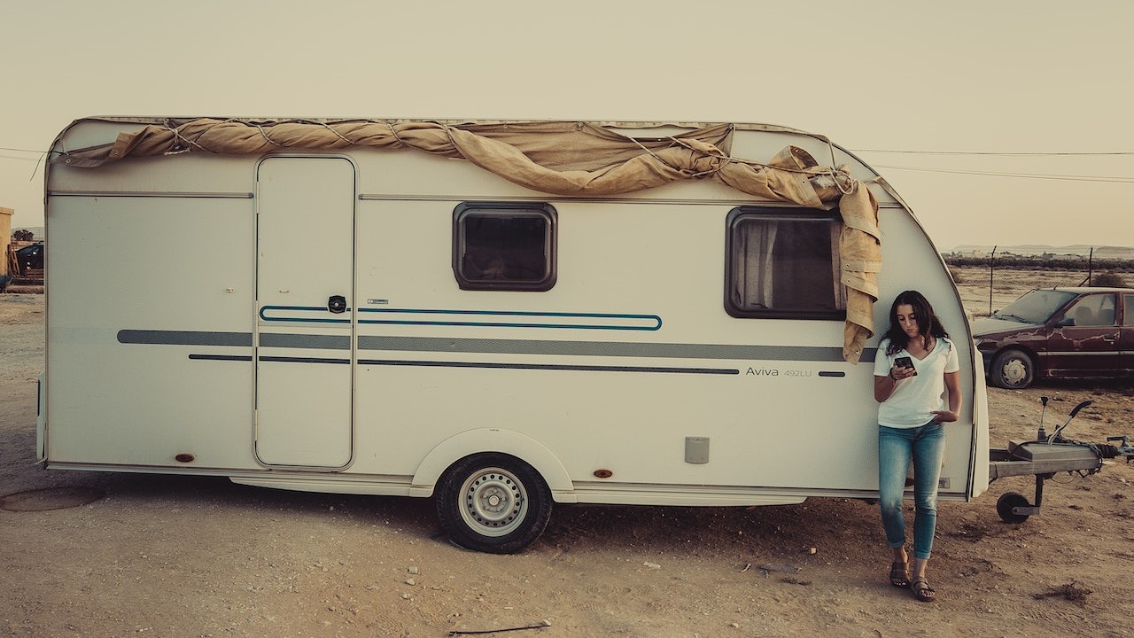 Woman holding a mobile phone near the white rv | Breast Cancer Car Donations