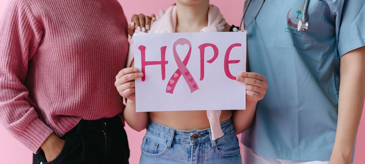 Woman in between of two person holding a hope sign | Breast Cancer Car Donations