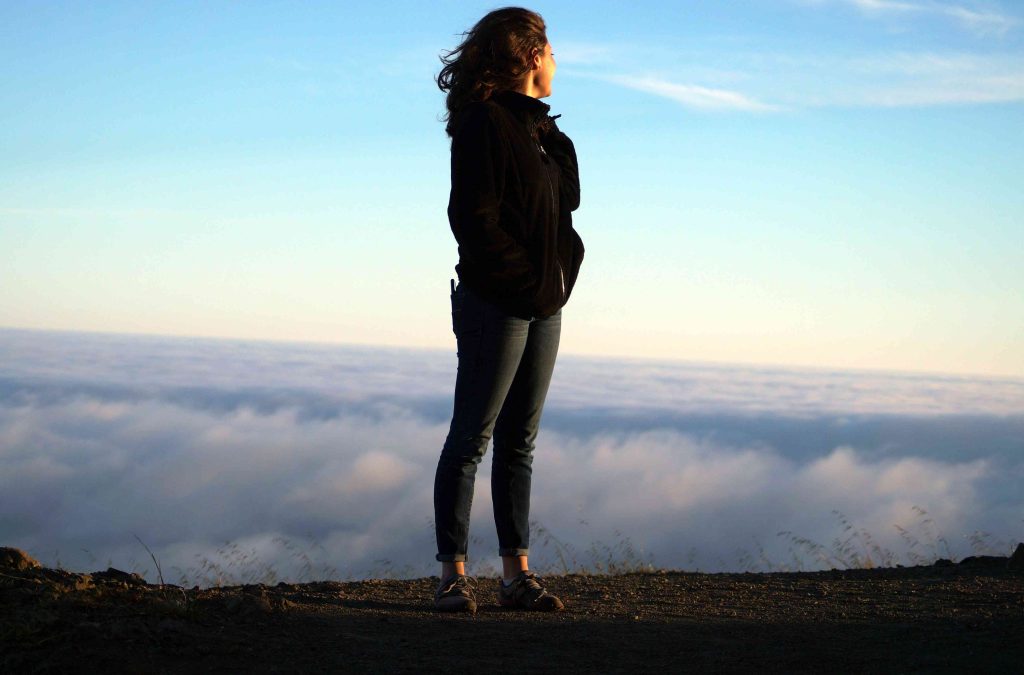Woman Standing in Mountains with Clouds | Breast Cancer Car Donations