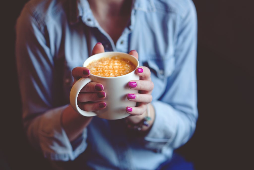 Woman Holding Cup of Latte | Breast Cancer Car Donations