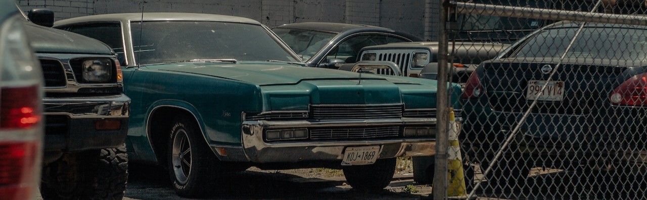 Green Car Parked Beside Gray Metal Fence | Breast Cancer Car Donations