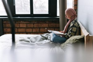 Woman Reading a Book while in Bed | Breast Cancer Car Donations