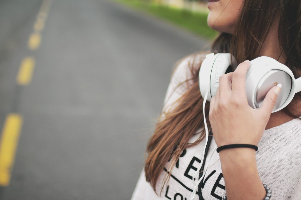 Woman Wearing Earphones Listening to Podcast | Breast Cancer Car Donations