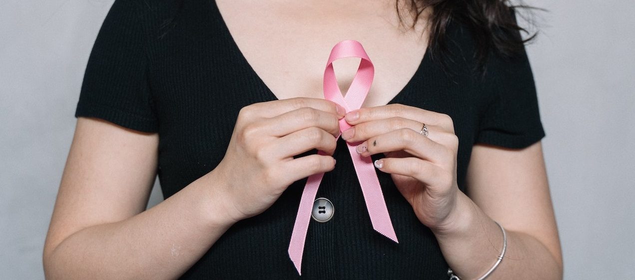 Woman holding pink ribbon | Breast Cancer Car Donations