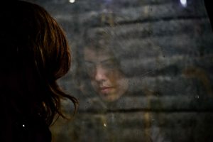 Anxious Woman Looking at a Glass Window | Breast Cancer Car Donations