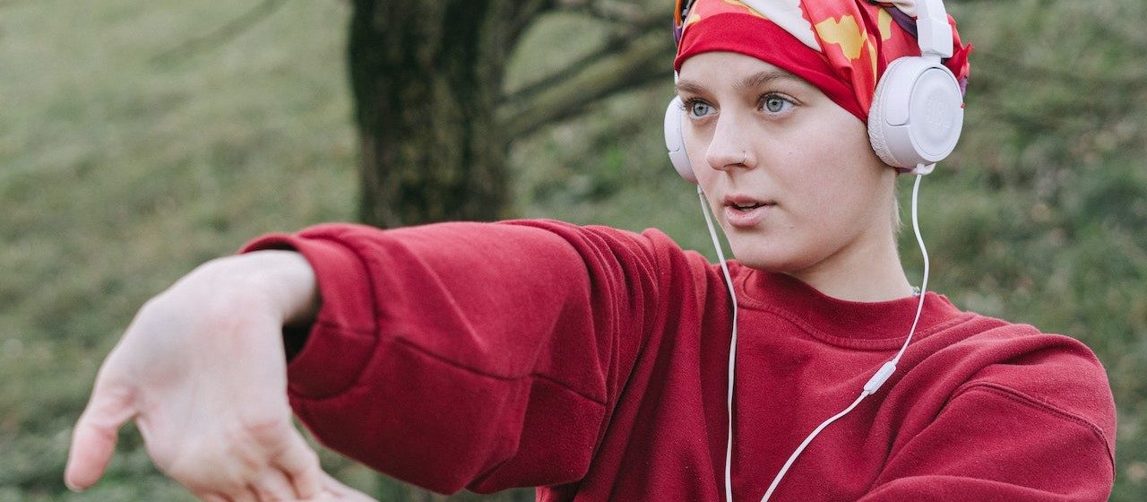 Woman Wearing White Headphones and Red Sweater | Breast Cancer Car Donations