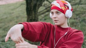 Woman Wearing White Headphones and Red Sweater | Breast Cancer Car Donations