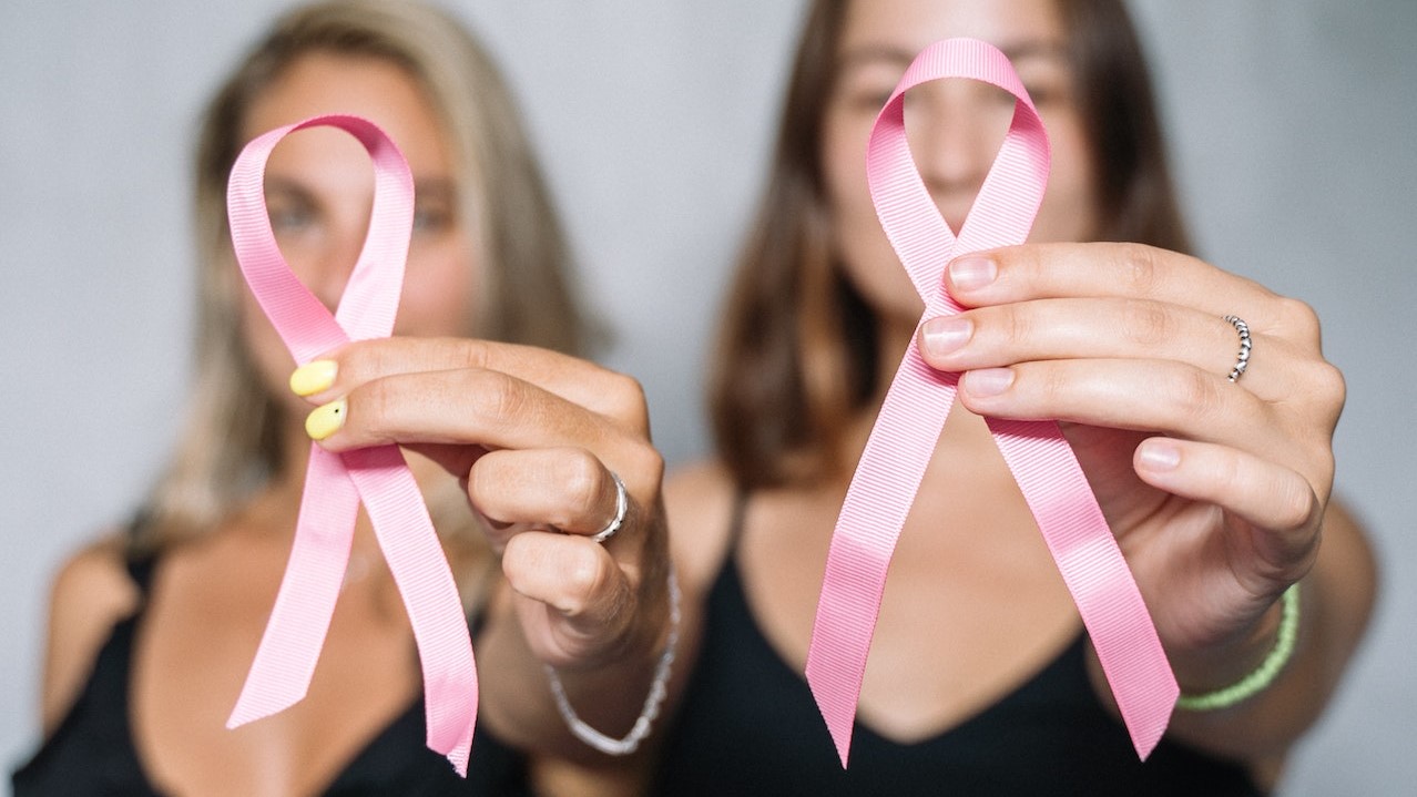 Women in Black Tank Top Holding Pink Ribbons | Breast Cancer Car Donations