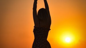 Carefree Woman In Long Dress Standing on A Rice Field During Sunset | Breast Cancer Car Donations