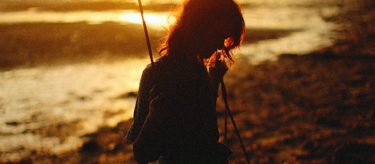 Silhouette of Woman Sitting on a Wooden SwingSilhouette of Woman Sitting on a Wooden