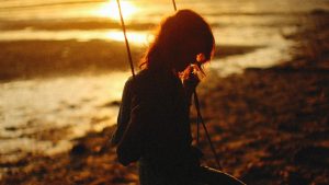 Silhouette of Woman Sitting on a Wooden SwingSilhouette of Woman Sitting on a Wooden