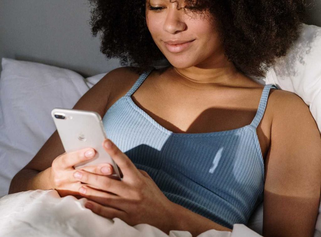 Woman Using Mobile Phone in Bed | Breast Cancer Car Donations
