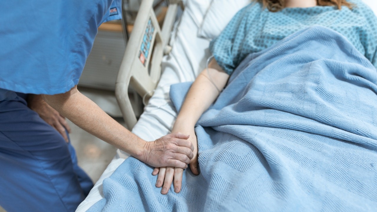 Person in Blue Scrub Suit Holding the Hand of a Patient | Breast Cancer Car Donations