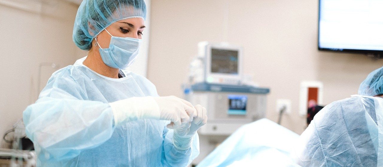 Woman in Blue Dress Shirt Wearing Blue Mask and White Latex Gloves | Breast Cancer Car Donations