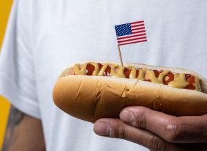 Person Holding a Hotdog with the US Flag | Breast Cancer Car Donations