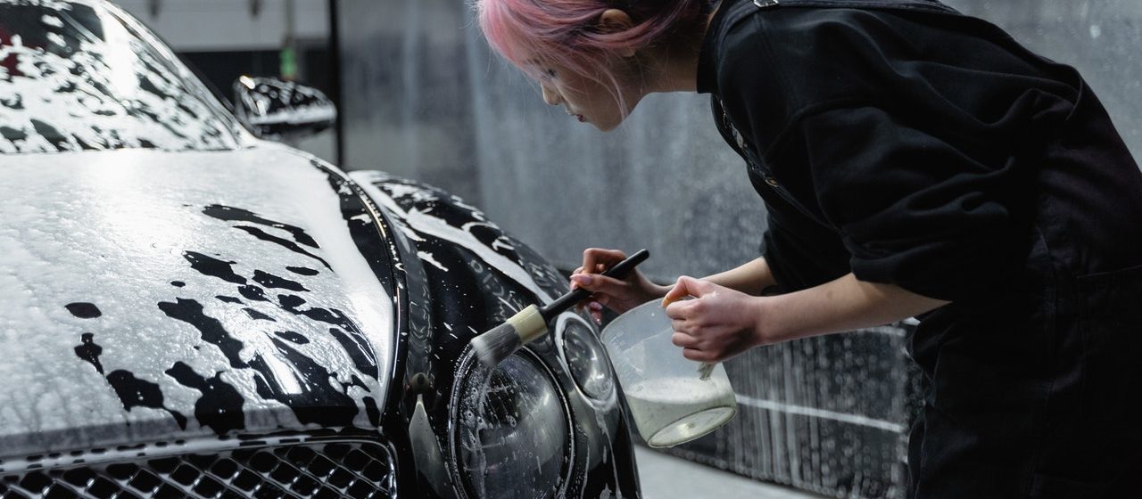 Woman Cleaning Car's Headlight | Breast Cancer Car Donations