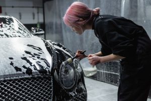 Woman Cleaning Car's Headlight | Breast Cancer Car Donations