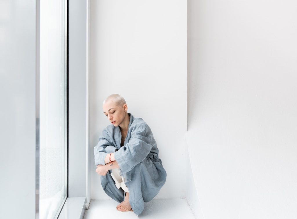 Woman Leaning on a White Wall | Breast Cancer Car Donations