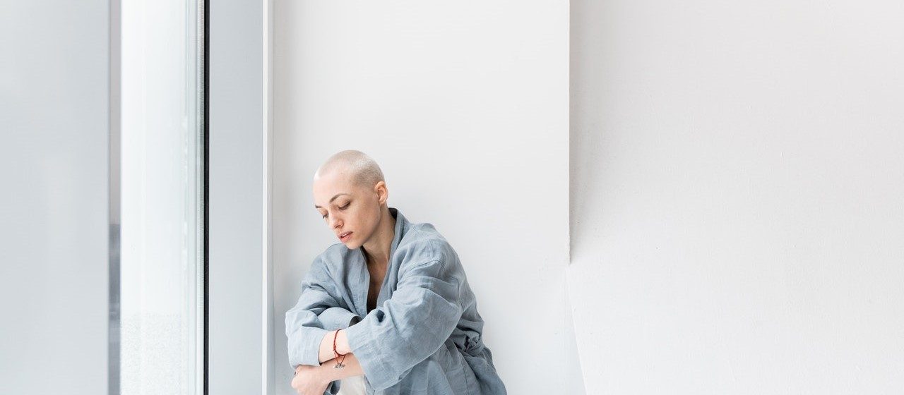 Woman Leaning on a White Wall | Breast Cancer Car Donations