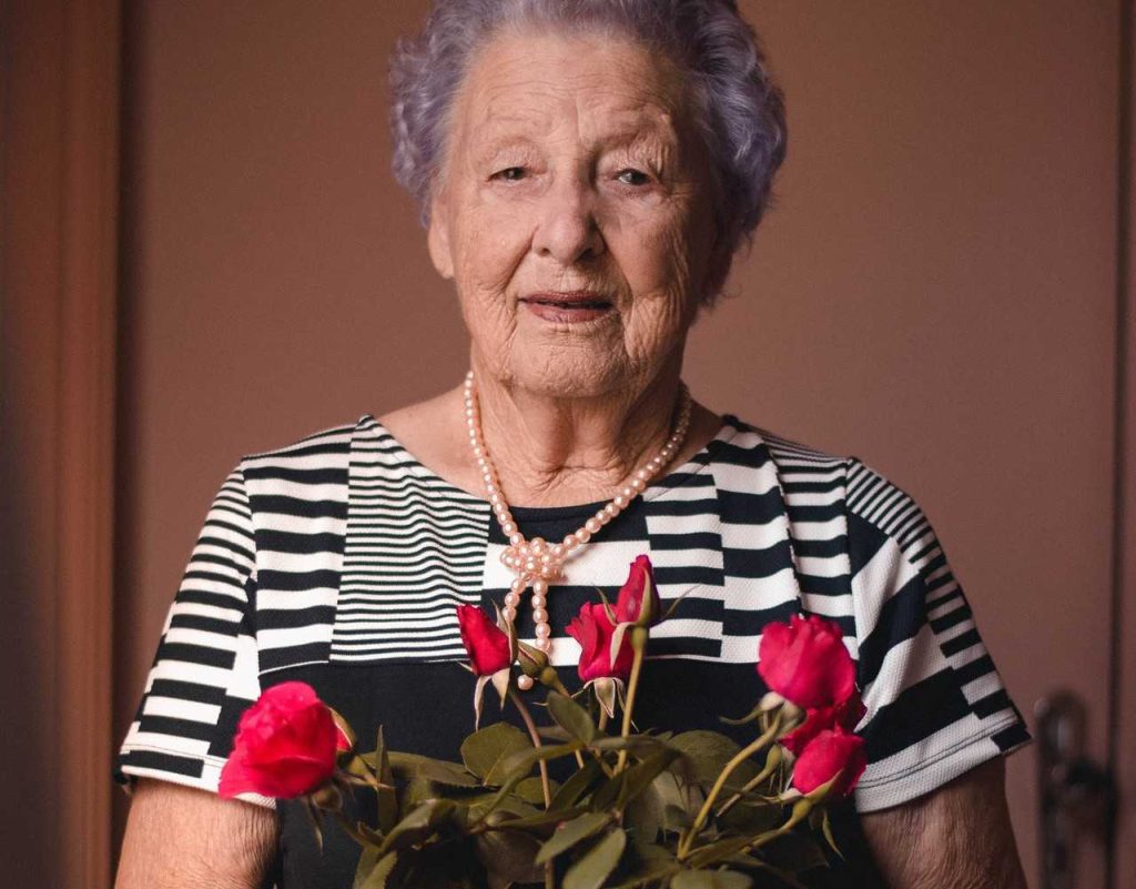 Portrait of an Old Woman Holding Flowers | Breast Cancer Car Donations