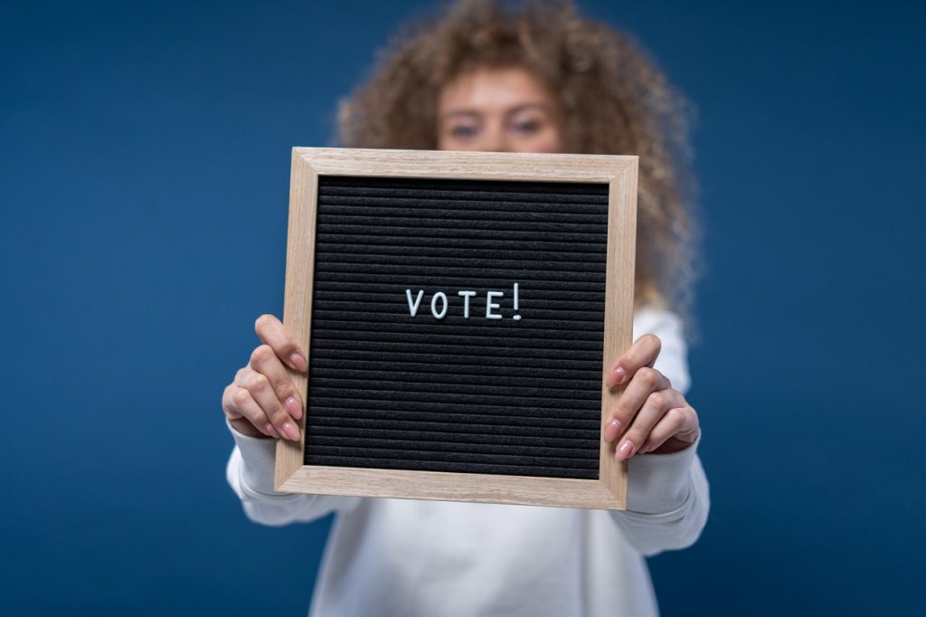 Woman Holding a Vote Sign | Breast Cancer Car Donations