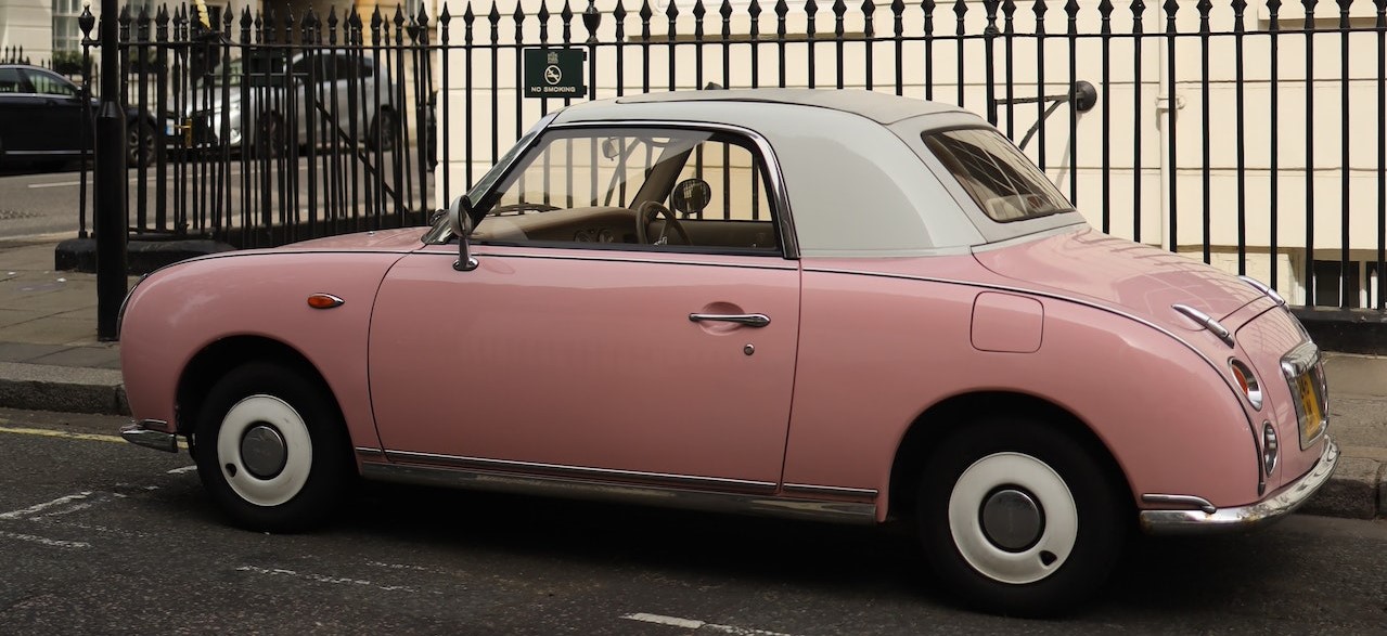 Pink Car Parked on Roadside Near Metal Fence | Breast Cancer Car Donations