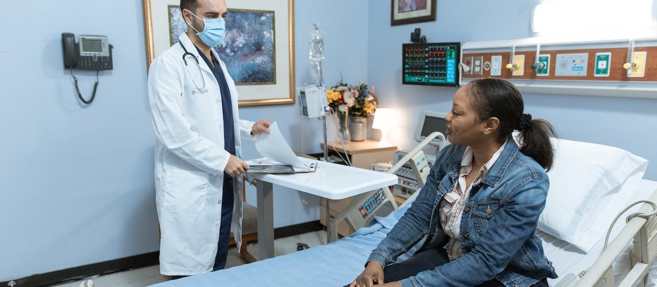 Woman in Blue Denim Jacket Sitting on Hospital Bed | Breast Cancer Car Donations