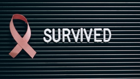 A Pink Ribbon beside a Survived Note on a Letter Board | Breast Cancer Car Donations