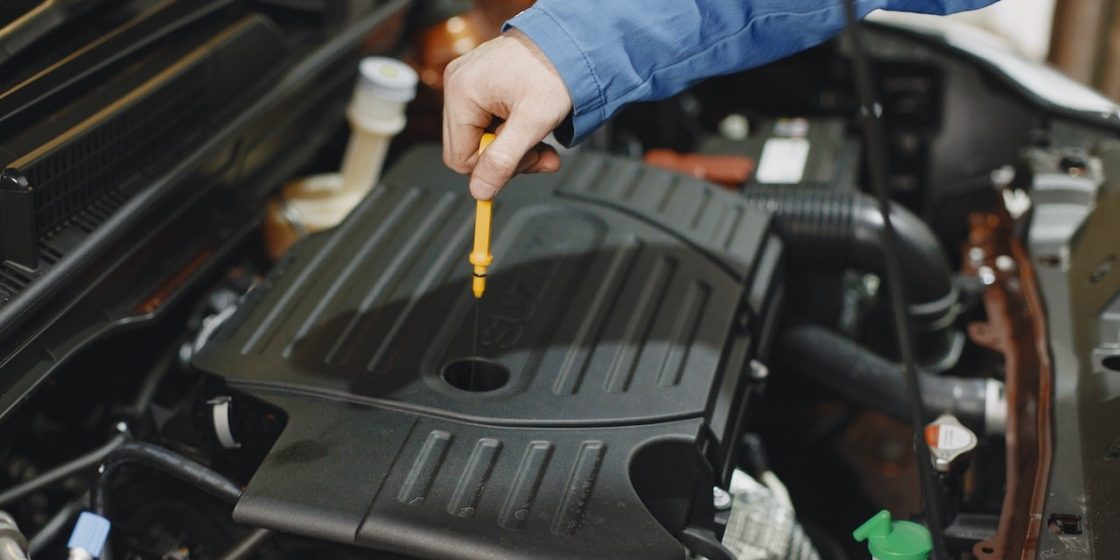 Person Checking the Oil of an Engine | Breast Cancer Car Donations