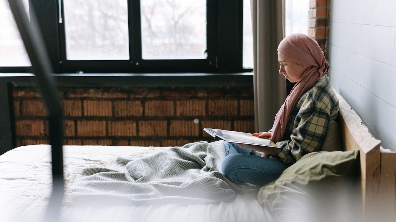 Woman Reading a Book while in Bed | Breast Cancer Car Donations