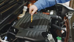 Person Checking the Oil of an Engine | Breast Cancer Car Donations