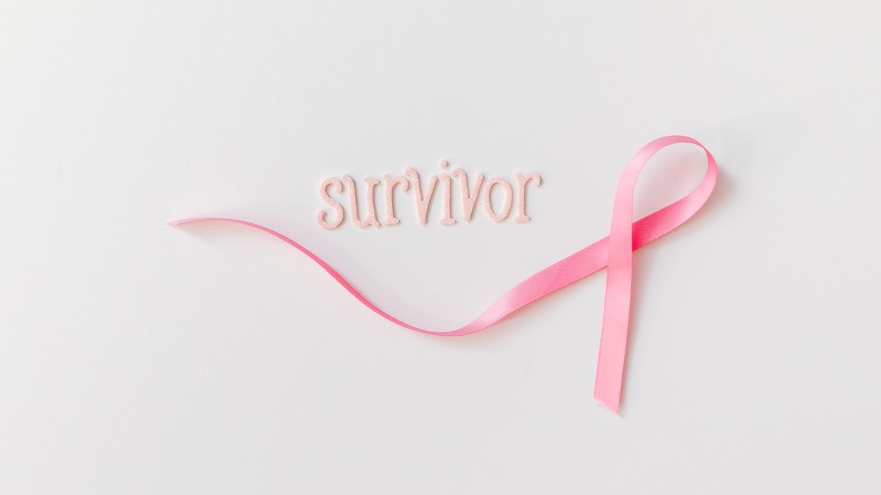 Pink Ribbon Beside Letters on a White Surface | Breast Cancer Car Donations