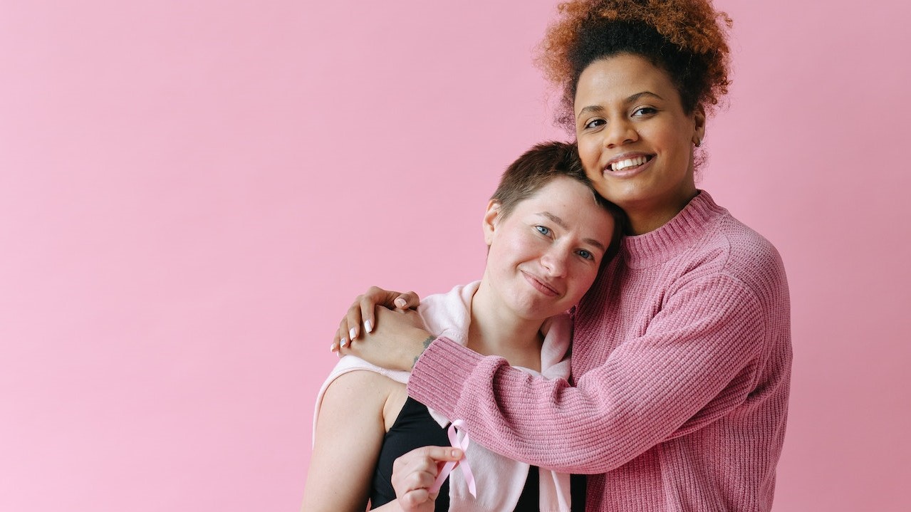 Women Hugging with a Pink Background | Breast Cancer Car Donations