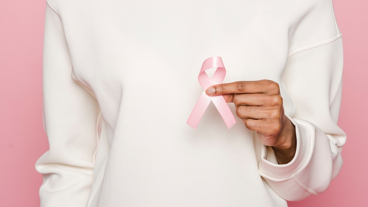 Woman In A White Hoodie Holding A Pink Ribbon | Breast Cancer Car Donations