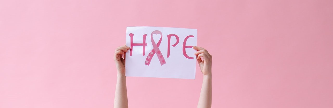 A Woman Holding a Placard with a Pink Ribbon | Breast Cancer Car Donations