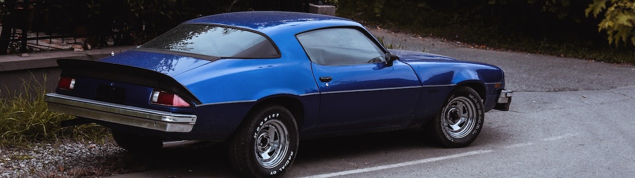 Blue Car Parked Beside a Concrete Fence |