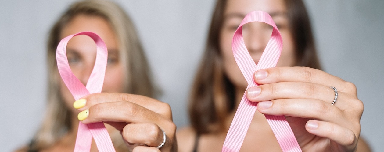 Blurred people holding pink ribbon | Breast Cancer Car Donations