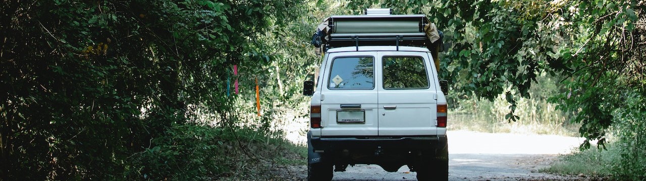 Car driving on road among green trees in countryside | Breast Cancer Car Donations