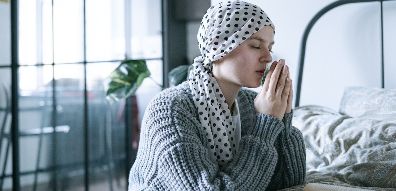 Girl on therapy praying on bed | Breast Cancer Car Donations