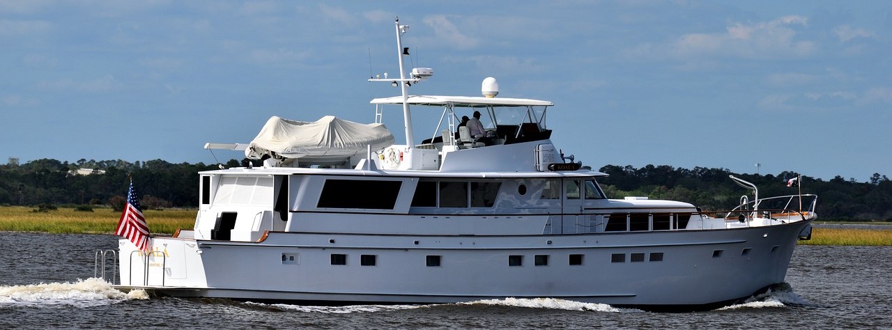 People riding white yacht with american flag | Breast Cancer Car Donations