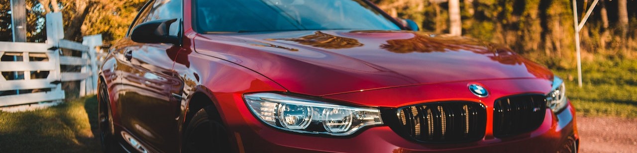 Shiny red car parked near trees in nature on sunny day | Breast Cancer Car Donations