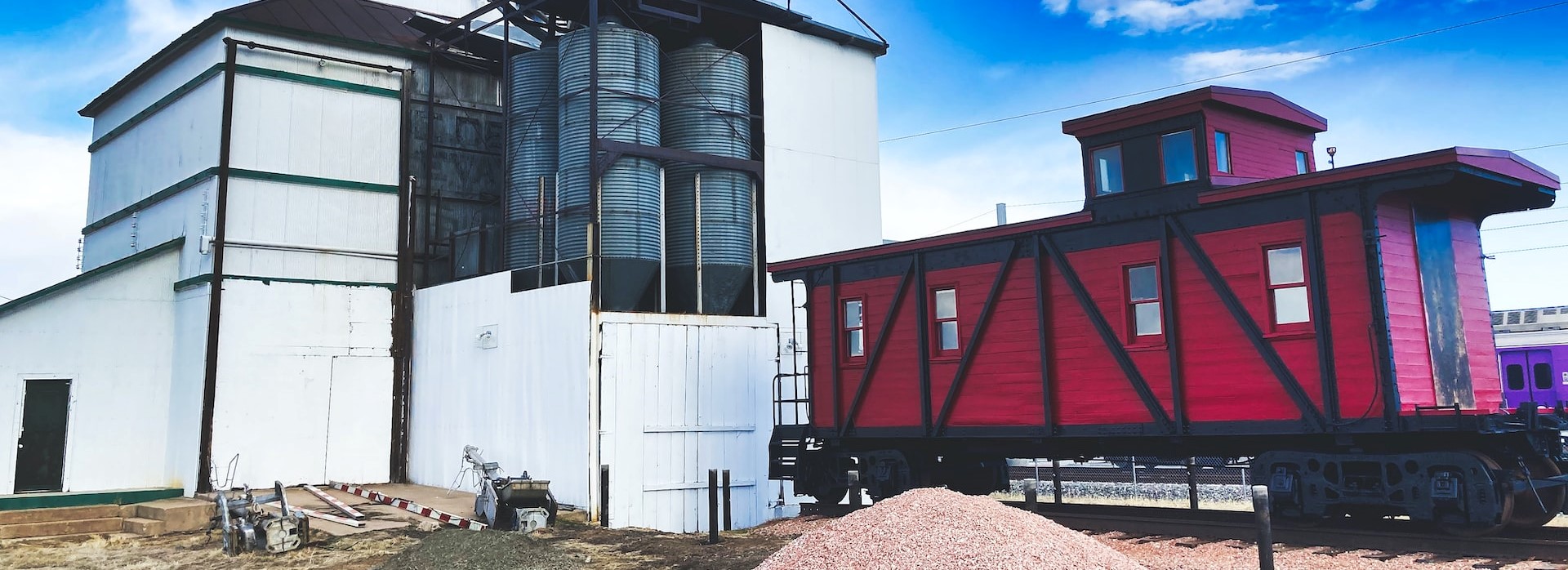 Siloed storage facility and caboose on rail track | Breast Cancer Car Donations