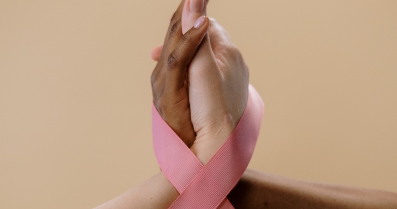 Two hand holding pink ribbon | Breast Cancer Car Donations