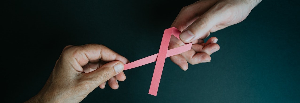 Two hands holding a pink ribbon | Breast Cancer Car Donations