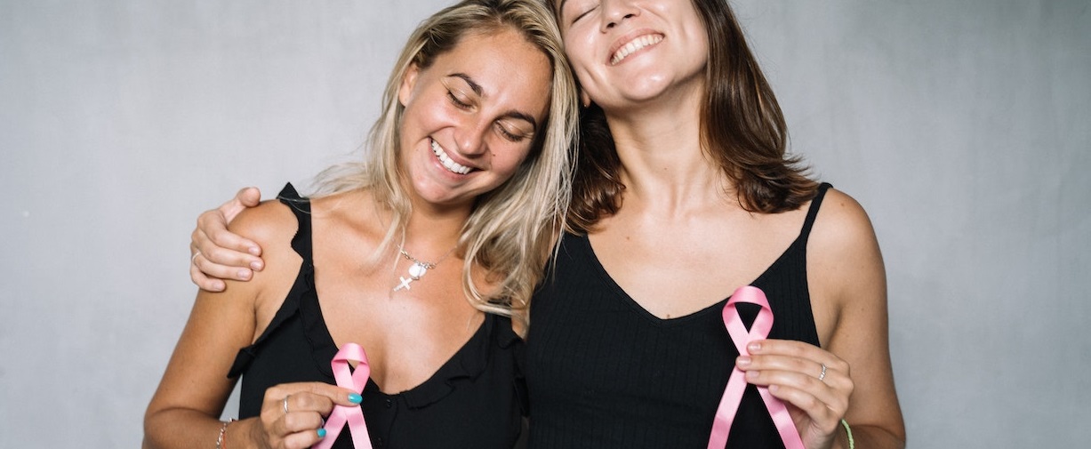 Two women holding pink ribbon | Breast Cancer Car Donations