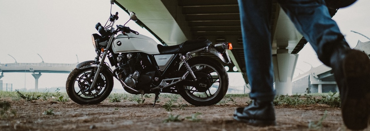 White motorcycle parked under bridge | Breast Cancer Car Donations