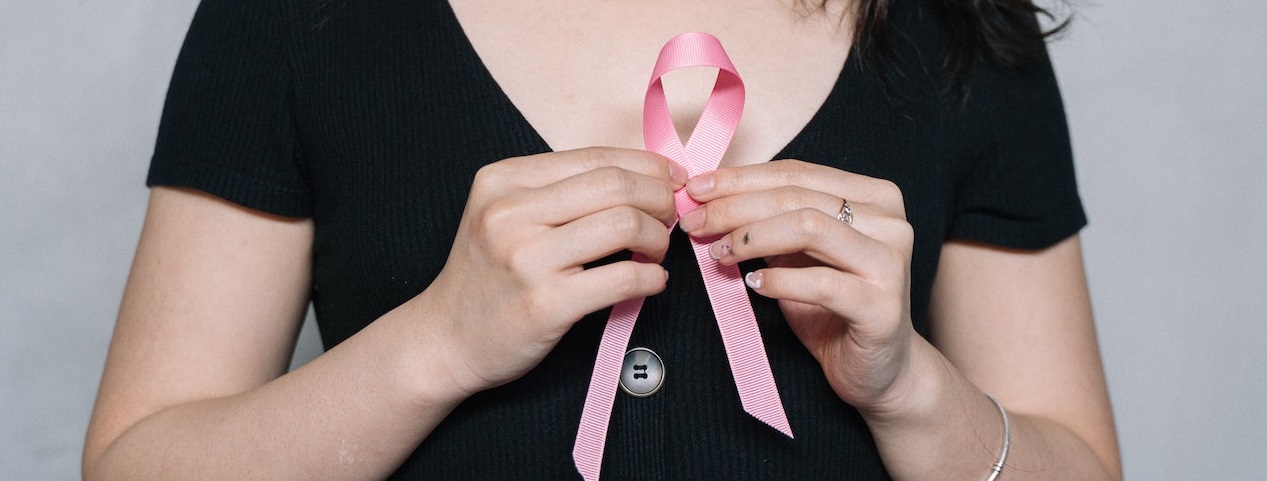 Woman in black holding pink ribbon | Breast Cancer Car Donations